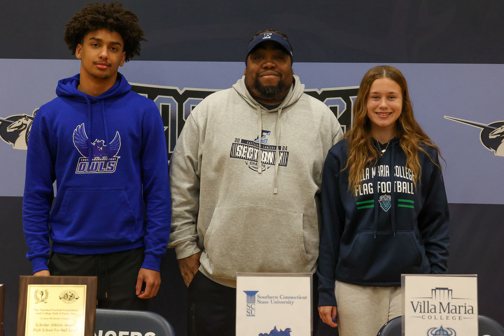 students stand with coach for a photo