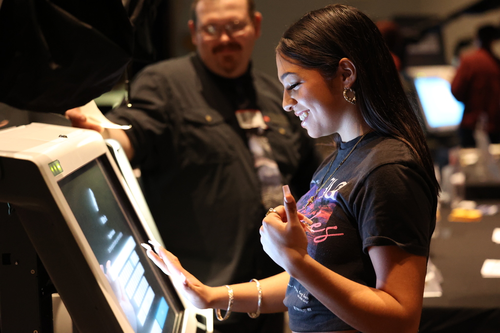student smiles and gives thumbs up at voting machine