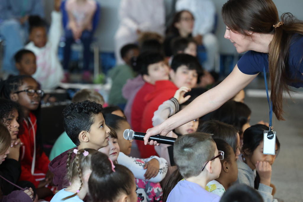 teacher holds mic up for student in the crowd