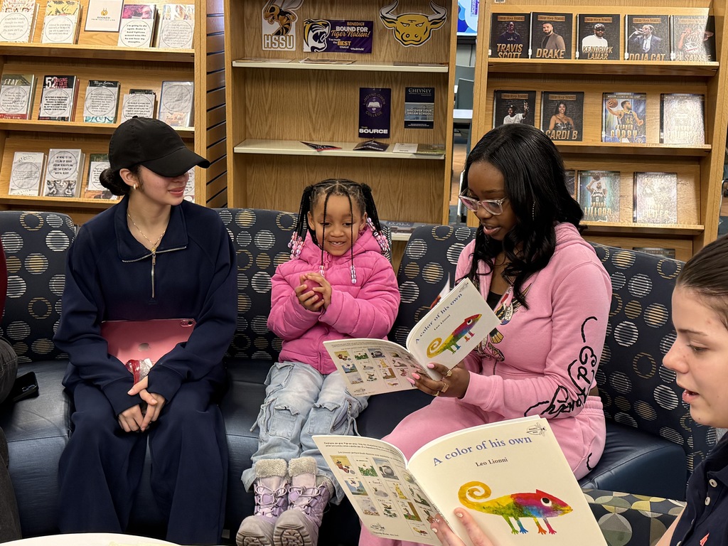 Families read books called A color of his own with a chameleon on the front on the couch 