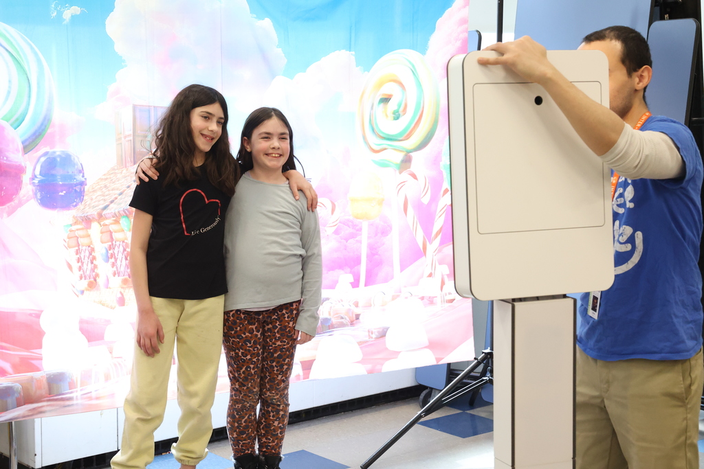 students pose for a photo at a photo booth with candy background
