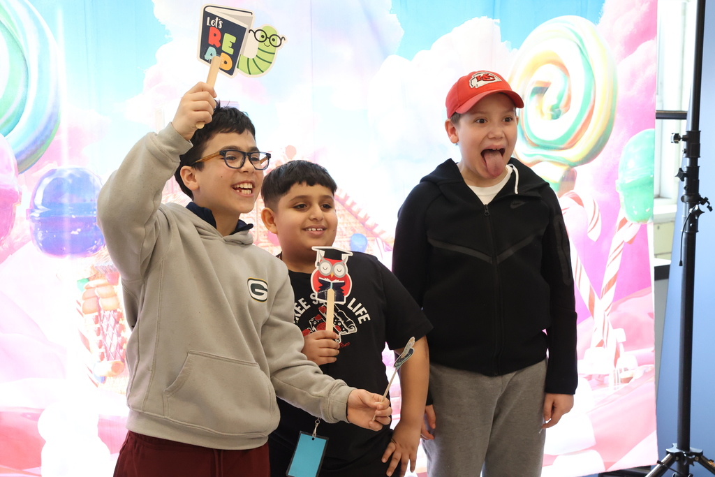 students make funny faces and poses while standing at a photo booth 