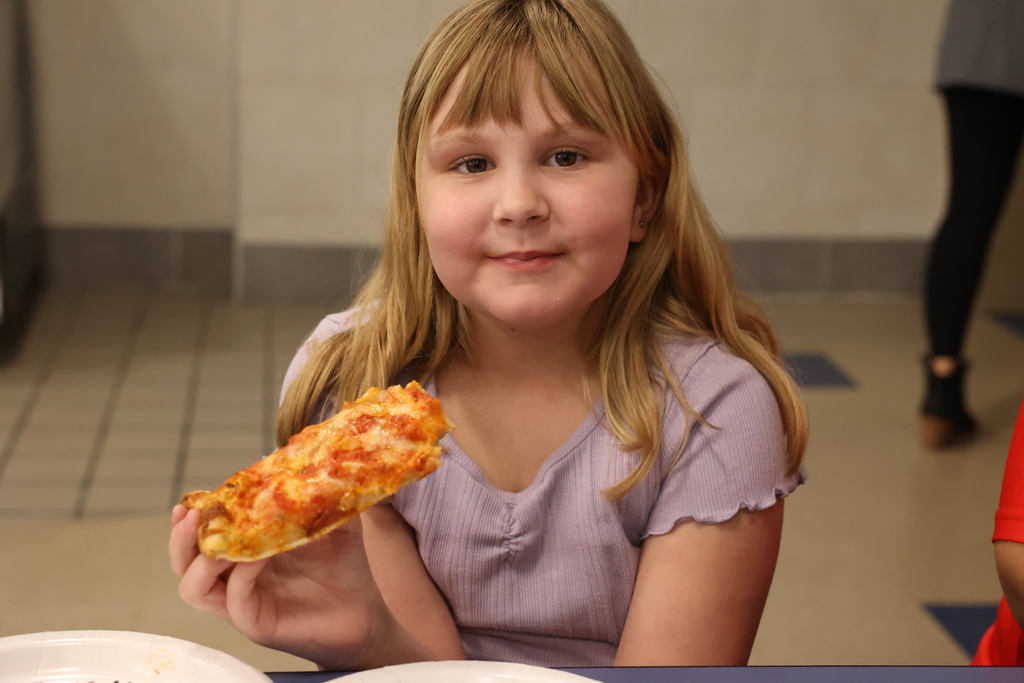 Student holds pizza and smile