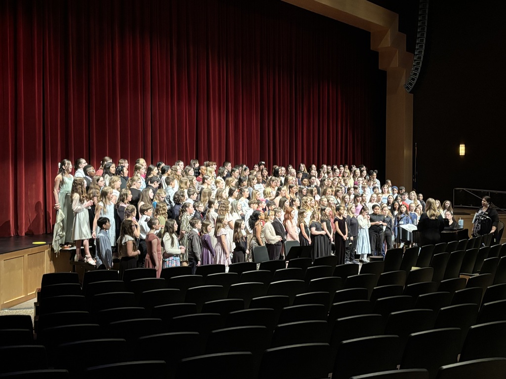 Choir sings together onstage in an auditorium 