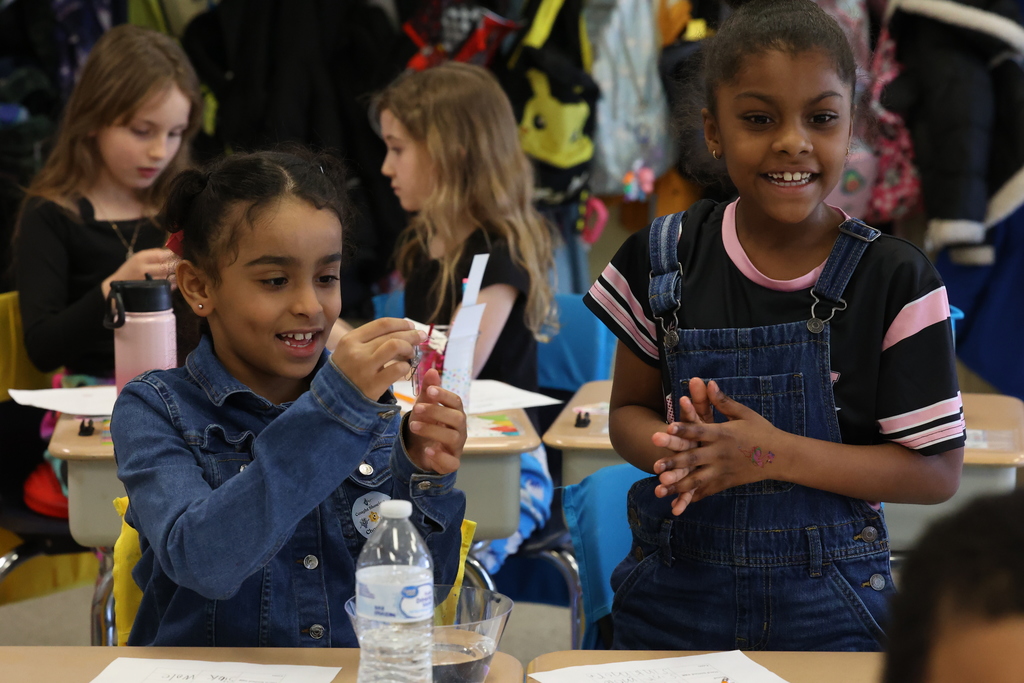 students smile and try to make paper clips float