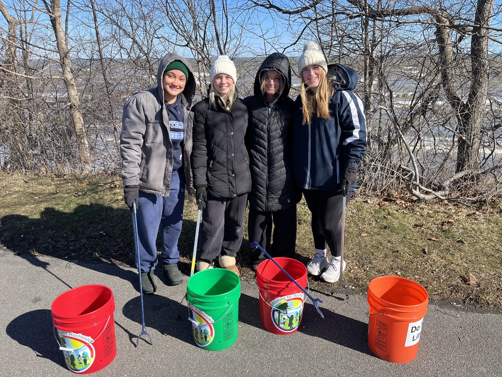 Students smile with buckets and sticks to pick up trash on the trails