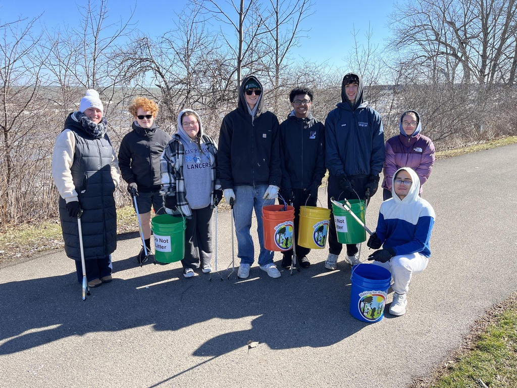 students smile with buckets and sticks to pick up trash from the trails