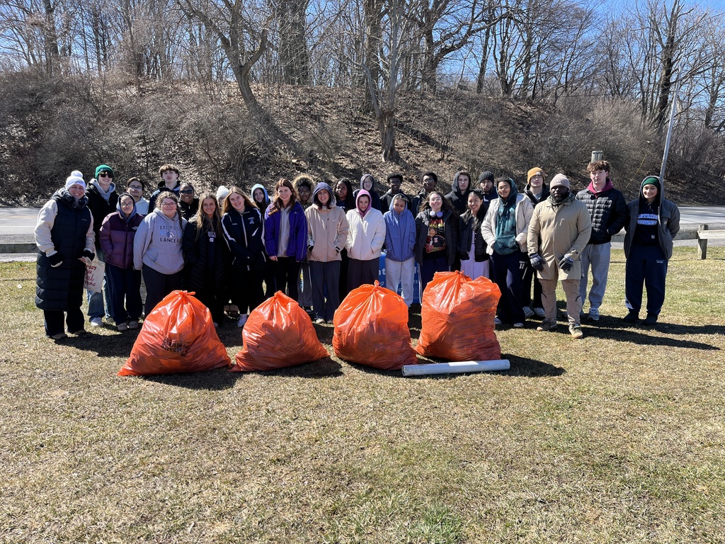 Students stand for a photo with four large bags of garbage in orange bags