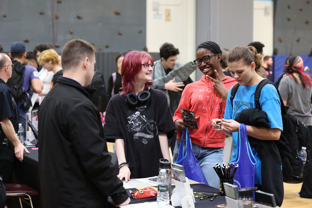 students smile and pose at career fair table