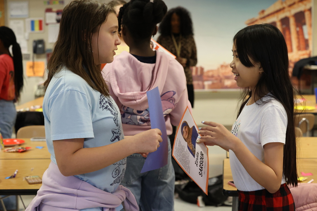 Students hold papers and talk about activity 