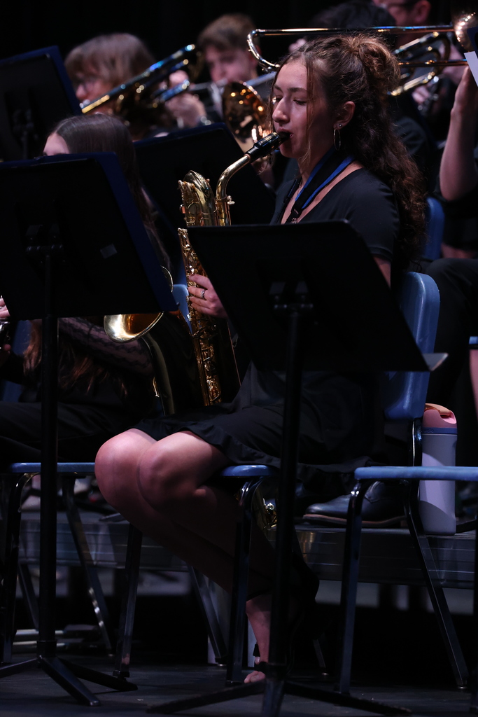 student reads music and plays saxophone on stage