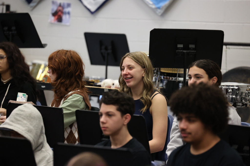 student smiles listening to speaker in music room
