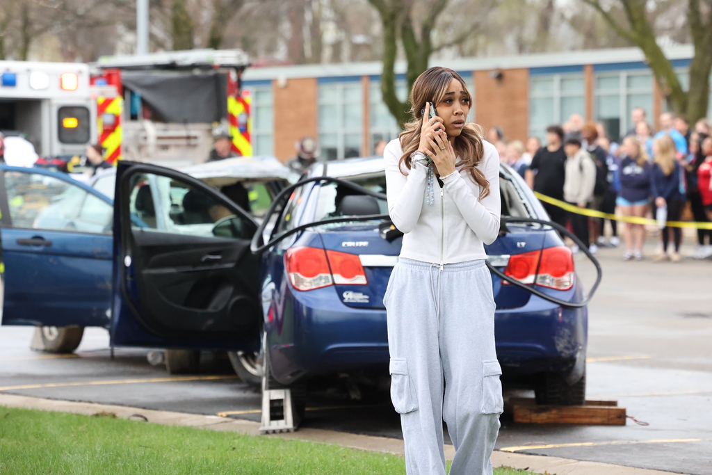 student acts while holding up a phone that there was a car accident