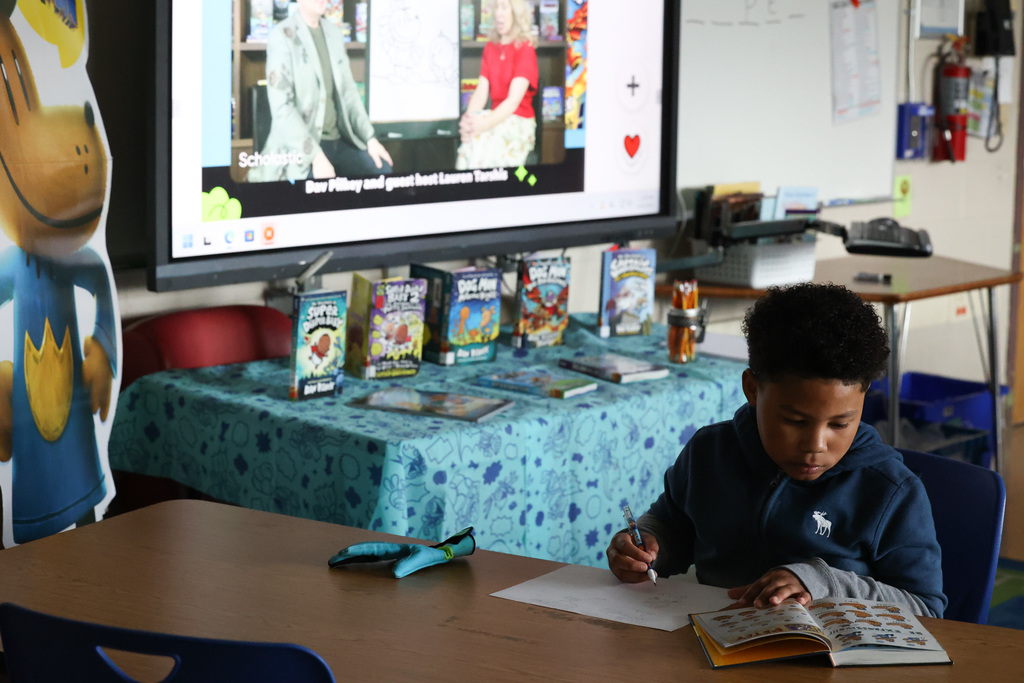 student practices creating cartoons with book