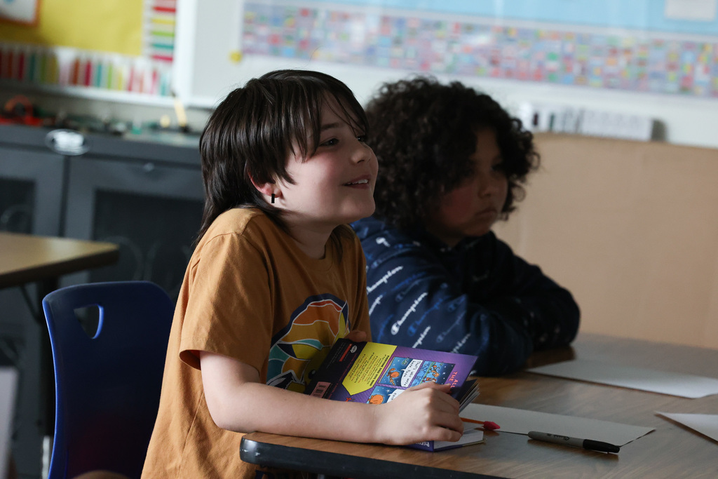 student smiles while holding book and watching interview
