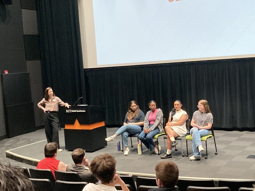 students listen to a panel of college students on stage