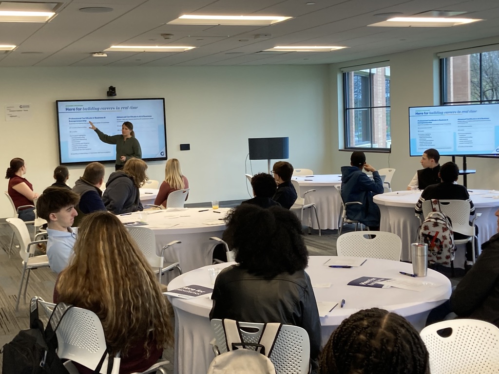 Students sit at tables with white tables cloths and learn about the Golisano Institute