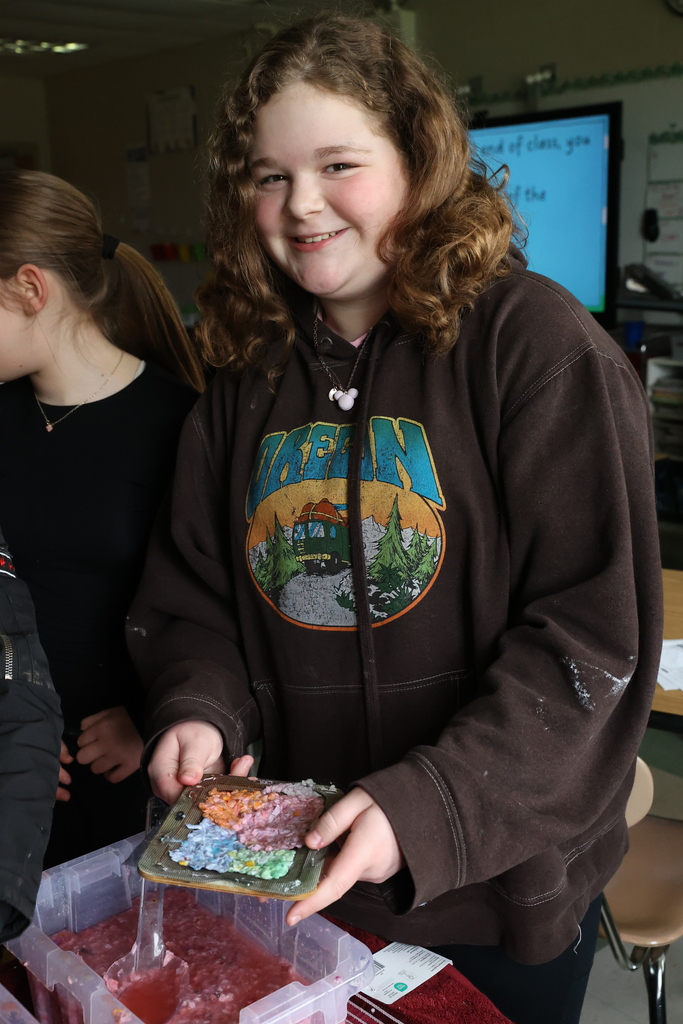 Student smiles with color paper making tray 