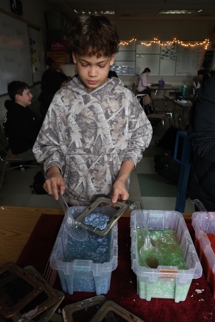 Student scoops blue paste into tray to make paper 