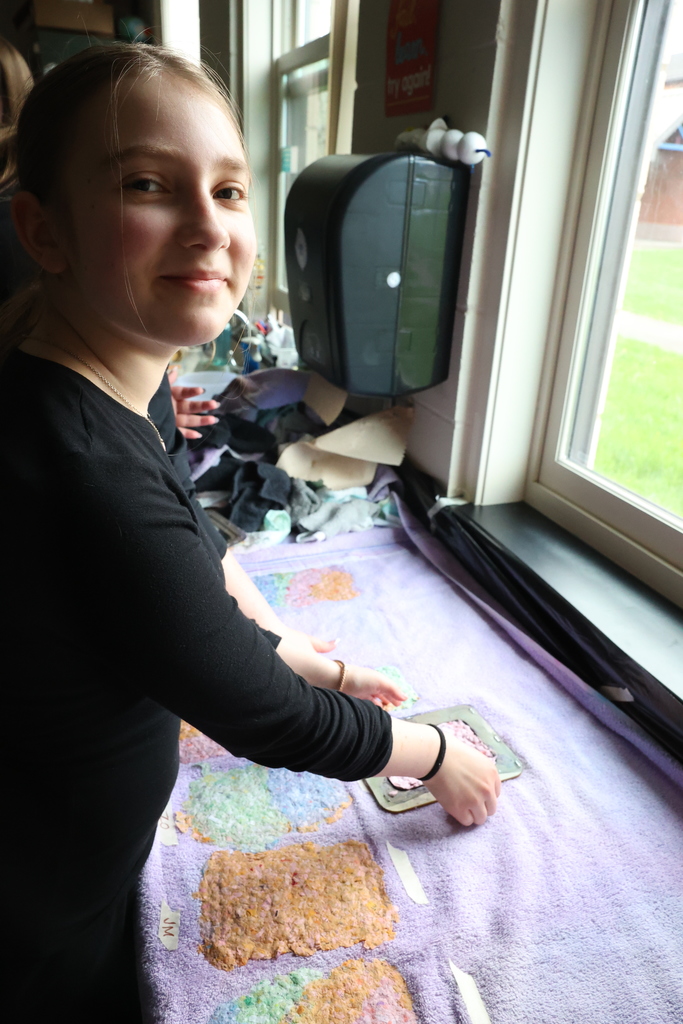 student smiles while placing paper on drying towel 