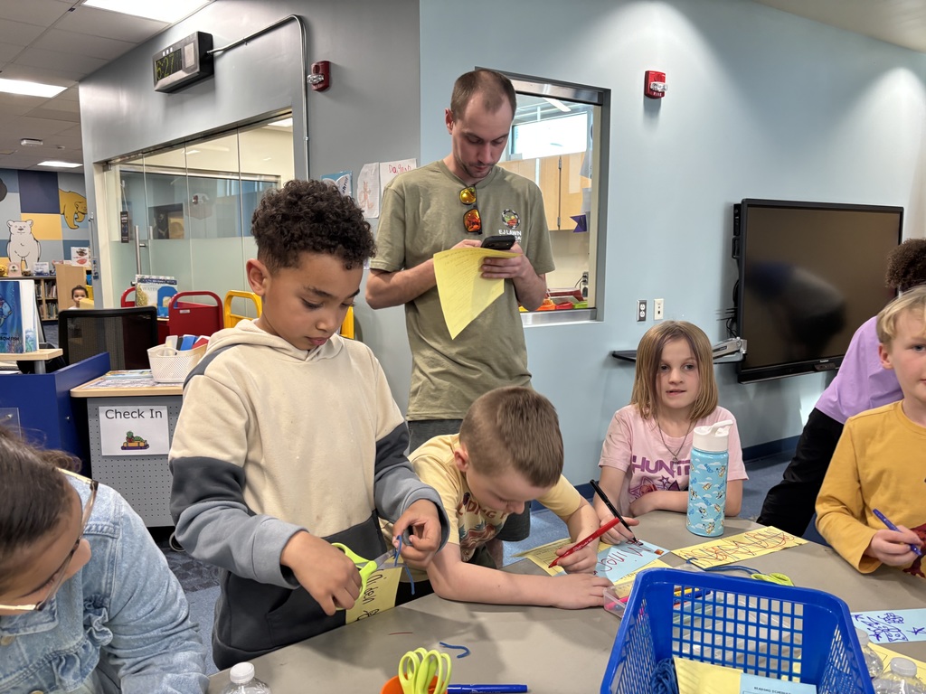 students and families work on a craft with scissors and drawing 