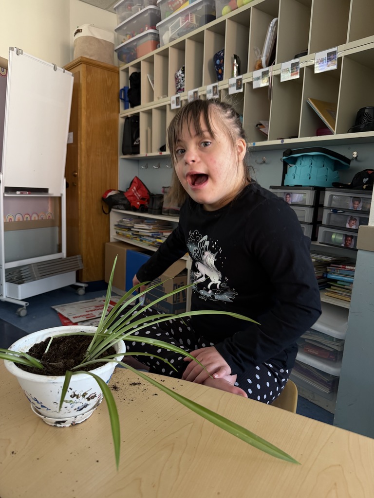 student smiles with potted plant