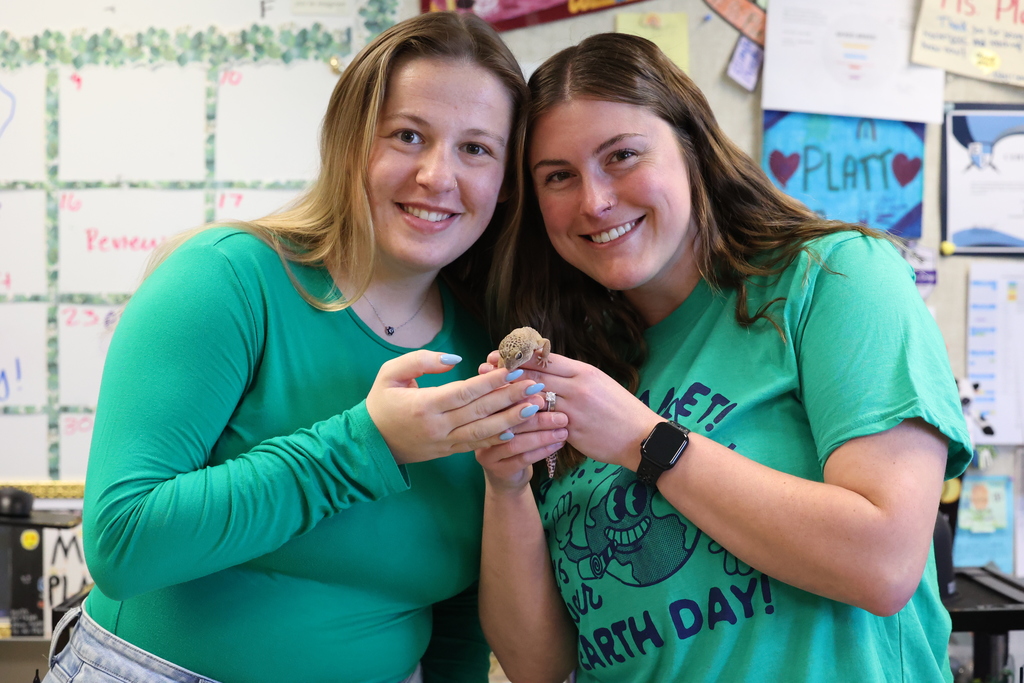 Teachers wear green to celebrate earth day and hold up getko