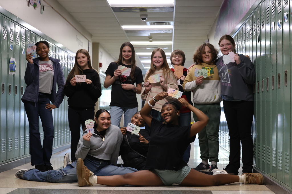 student holds up signs and smile and do splits in the hallway