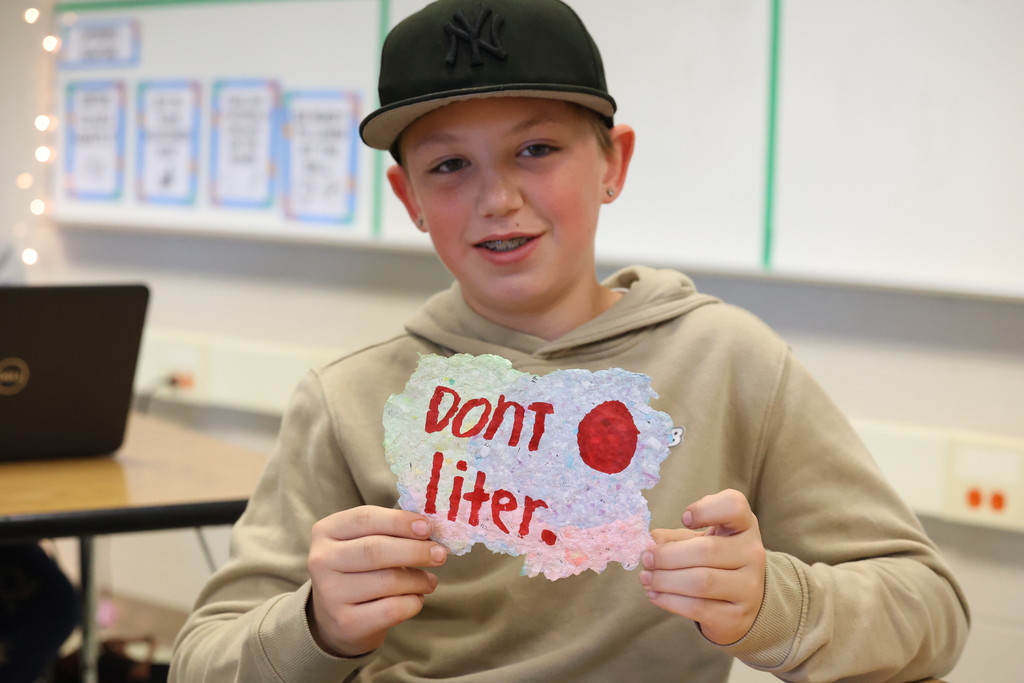 student holds up sign that says dont liter