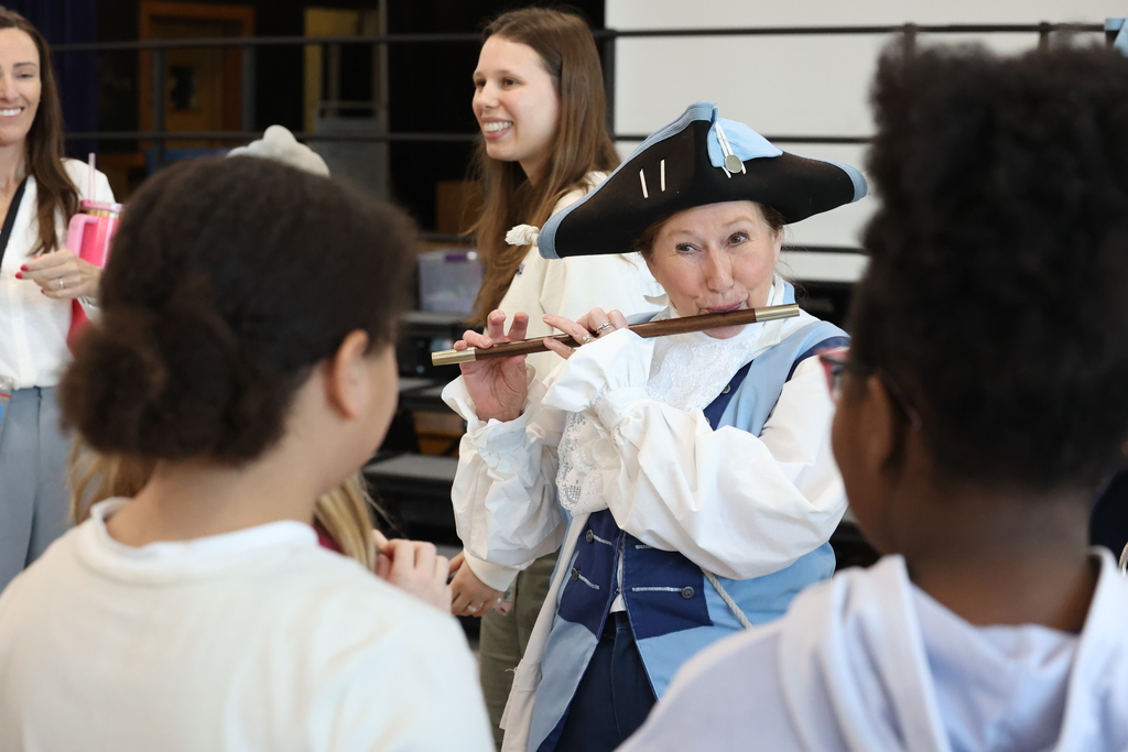performer plays the fife for students