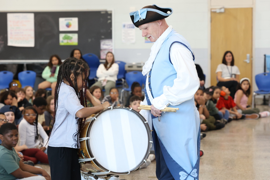 performers lets student test out drum to see how heavy it is