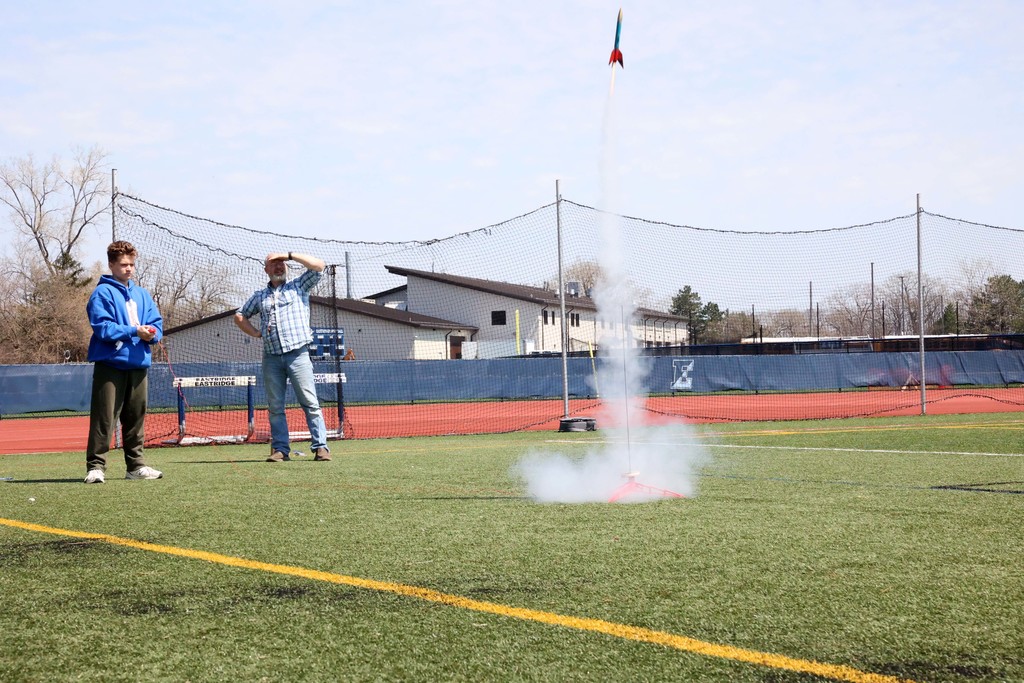 Student hits button while launching rocket on the football field