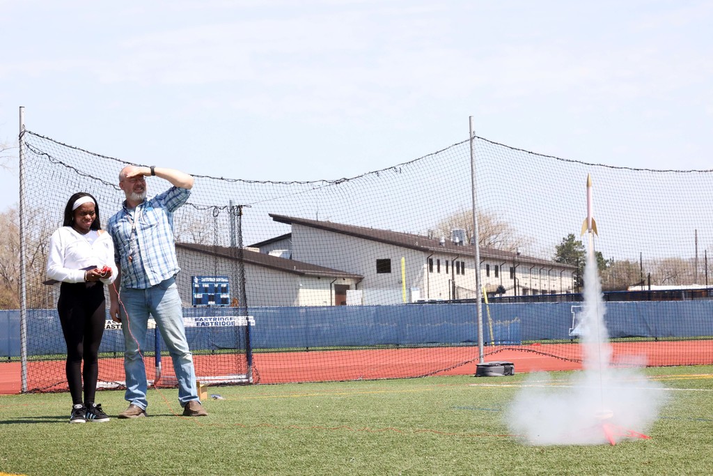 Student hits button while launching rocket on the football field