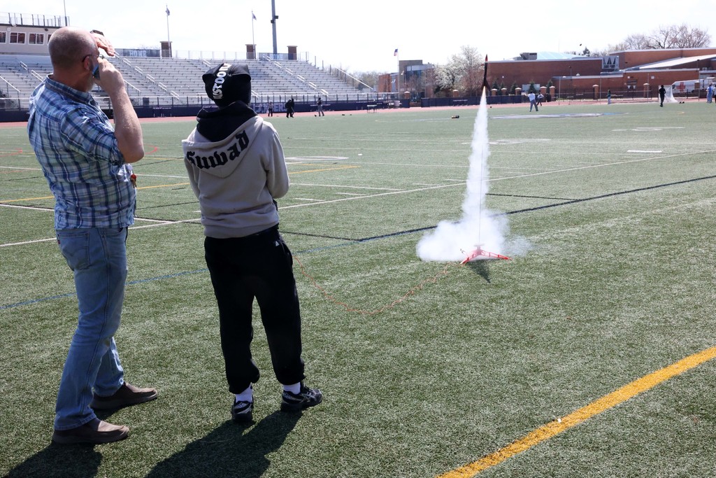 Student hits button while launching rocket on the football field