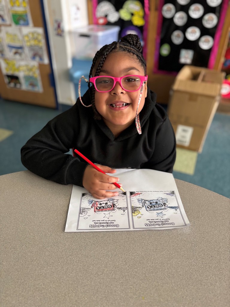 Student smiles and colors card with red pencil