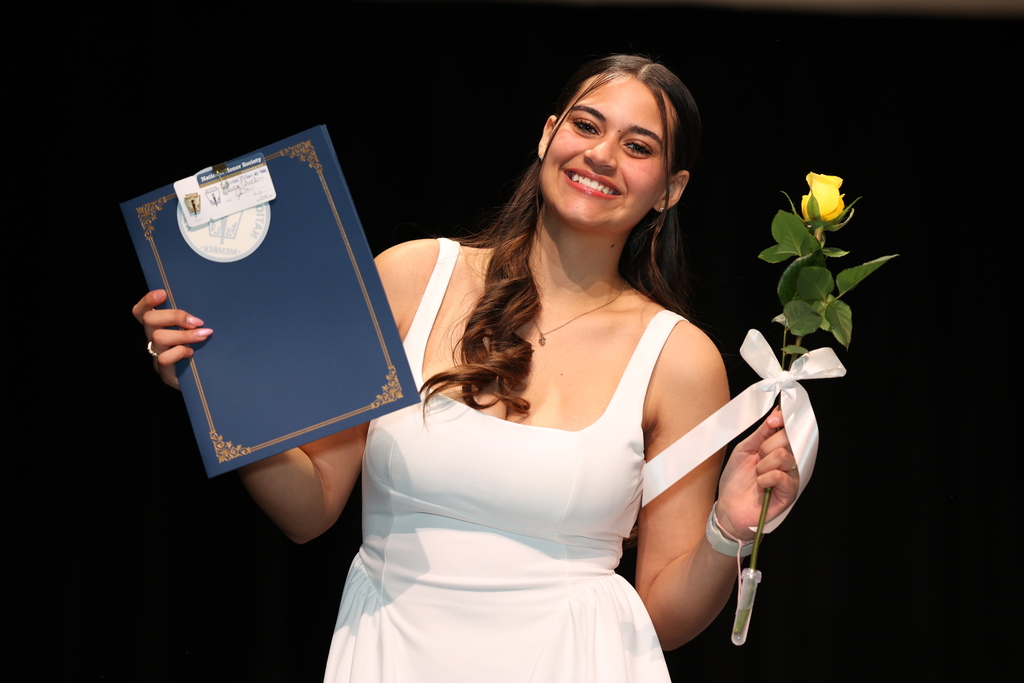 student holds up certificate and flower 