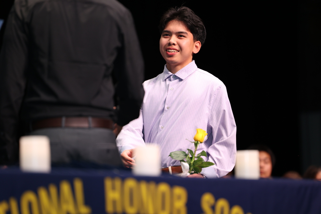 student smiles with flower in hand while being inducted into NHS