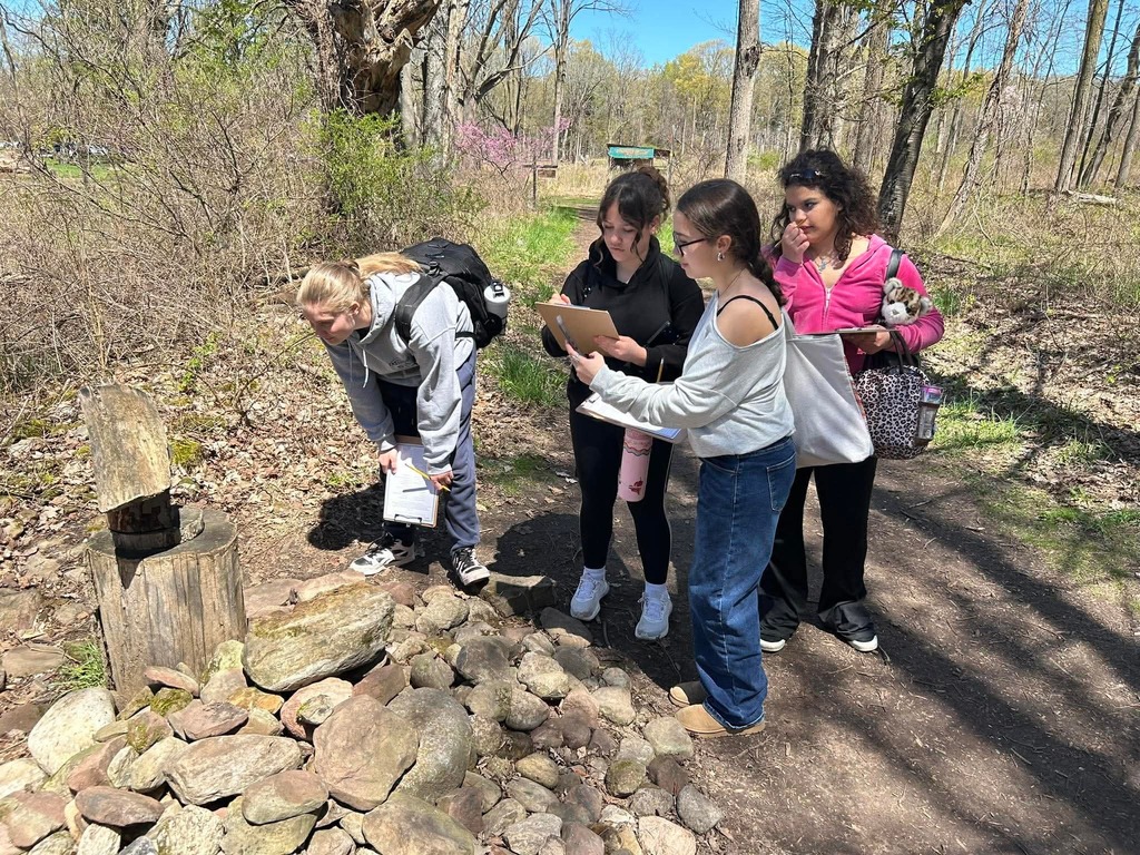 students participate in a scavenger hunt on the trail with clipboards