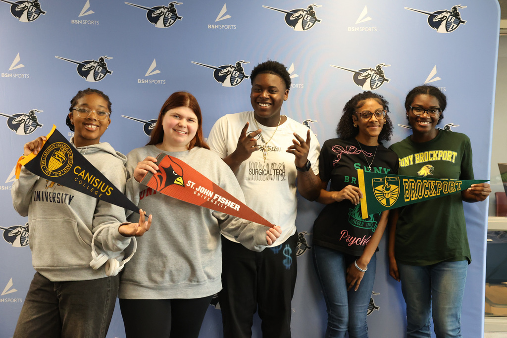 students hold up a variety of college flags celebrating Decision Day
