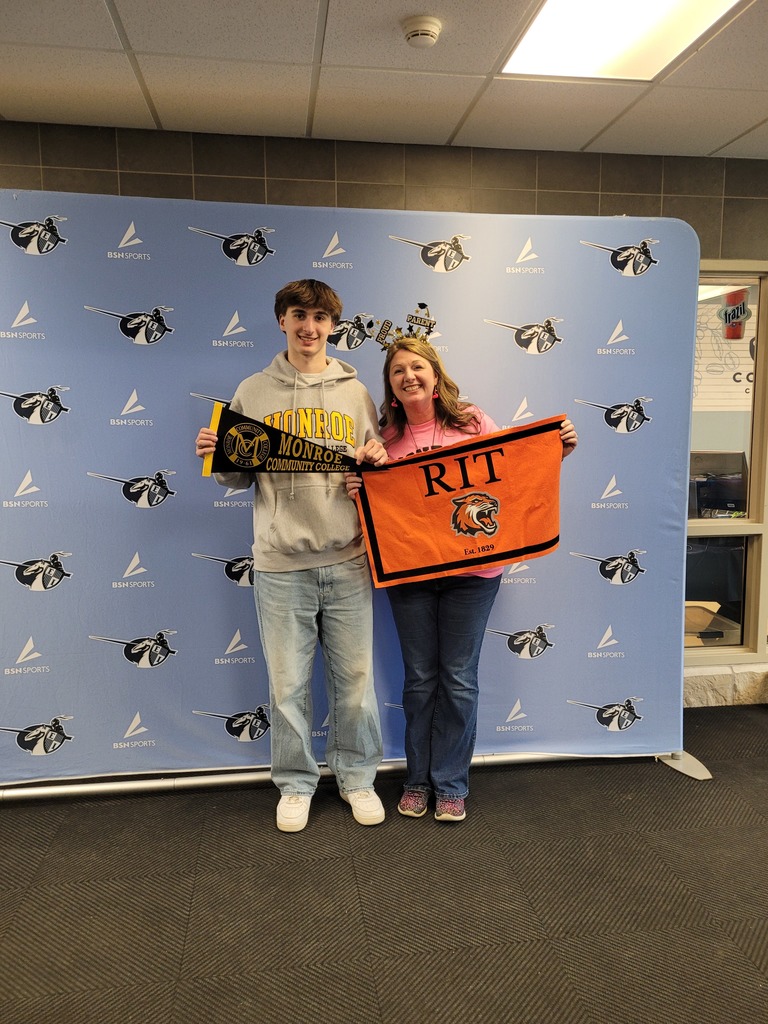 student and staff member hold up MCC and RIT flag for a photo