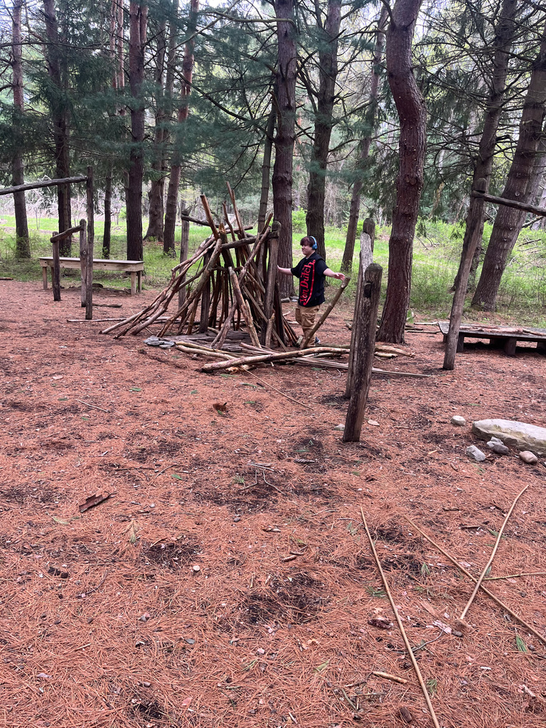 student looks at wood pile tee pee
