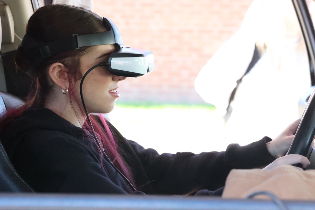 Student puts on glasses and sits in car for driving stimulation