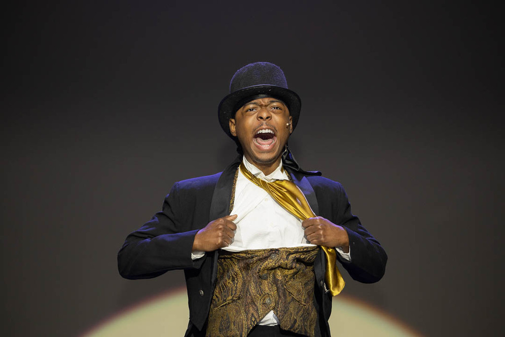 Actor sings while ripping open suit and shirt with top hat on