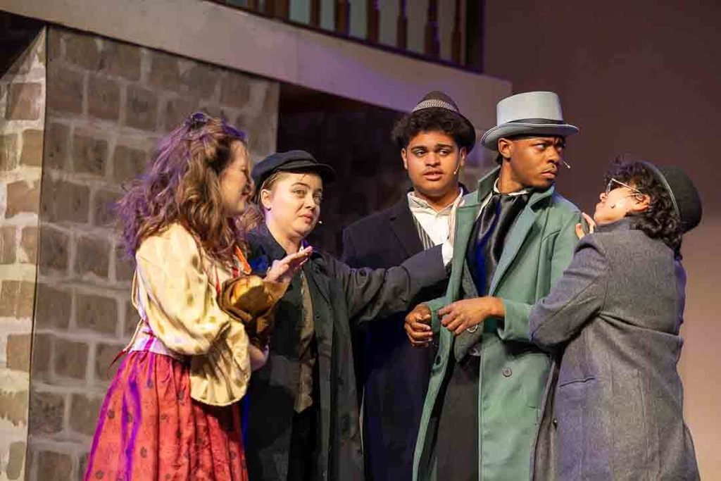 Actors act on stage together in costumes during Les Mis performance