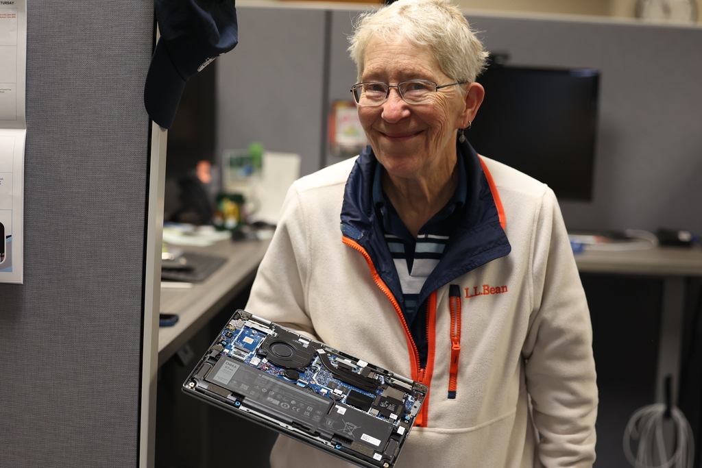 IT staff holds up take a part computer and smiles