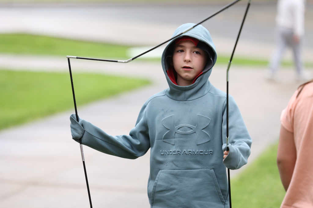 student holds up tent building equipment