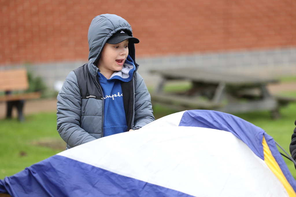 student helps put up tent outside