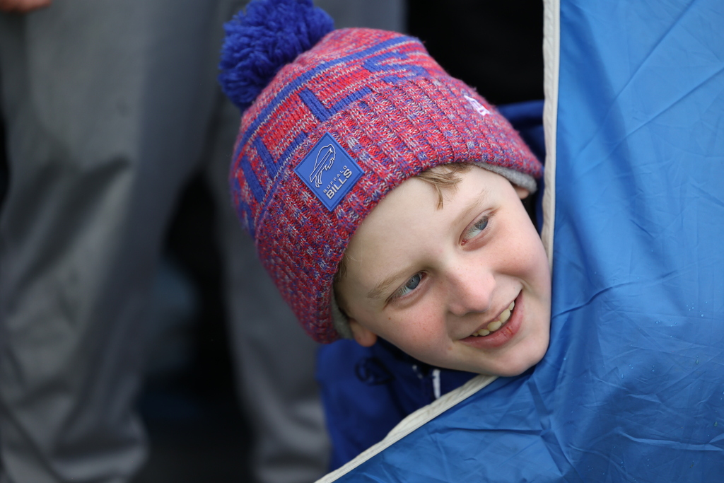 Student peers our of tent with bills hat on 