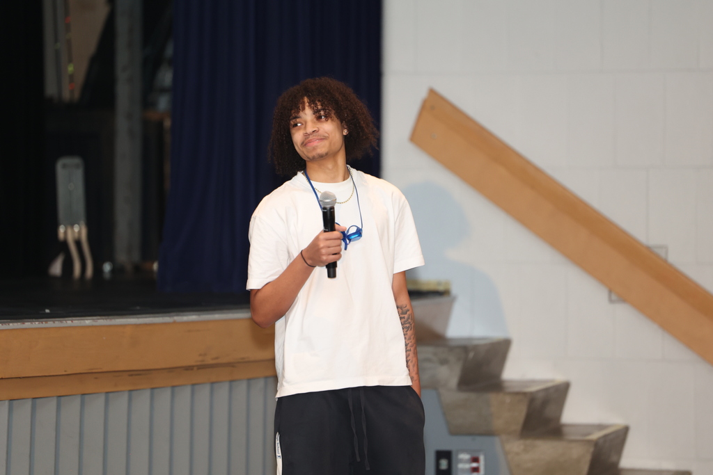 student holds up mic and smiles 