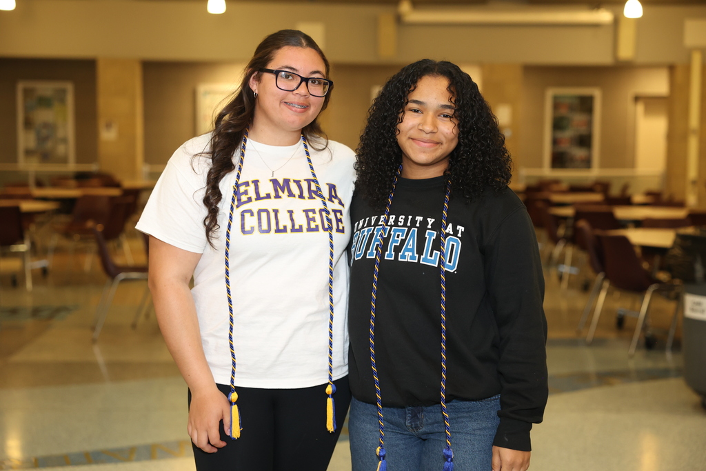 students smile with cords with college shirts on